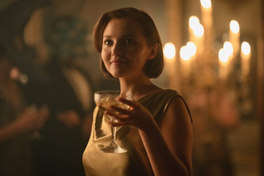 "Woman in a gold dress holding a drink at an elegant, dimly lit party with candlelight in the background, creating a warm, sophisticated atmosphere."